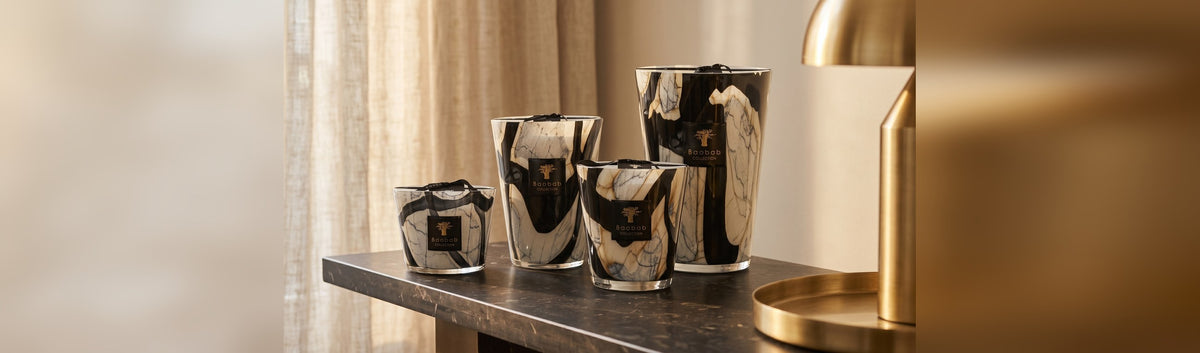 Quatre formats de bougies Baobab Collection en verre soufflé posés sur une console, du plus petit au plus grand