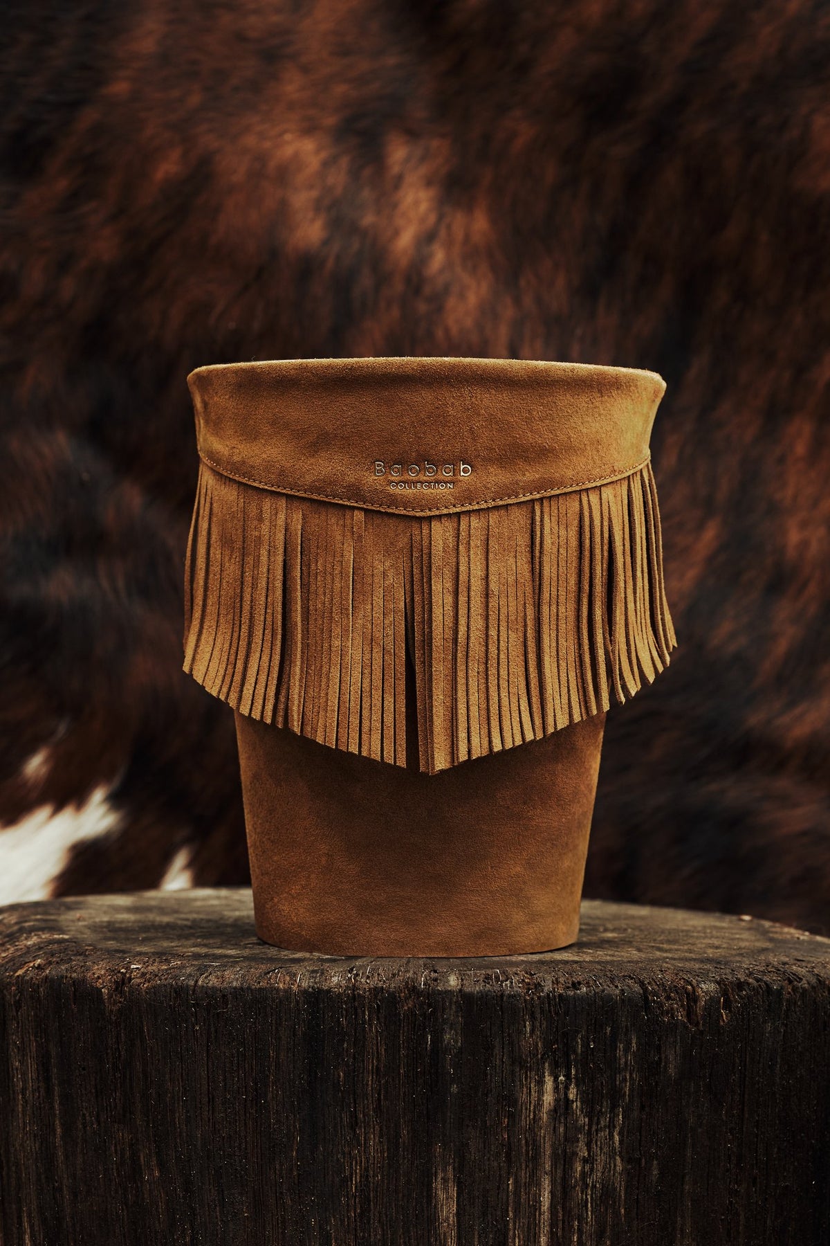 Détail des franges en cuir cognac de la bougie Baobab Wild Bill, sur une souche