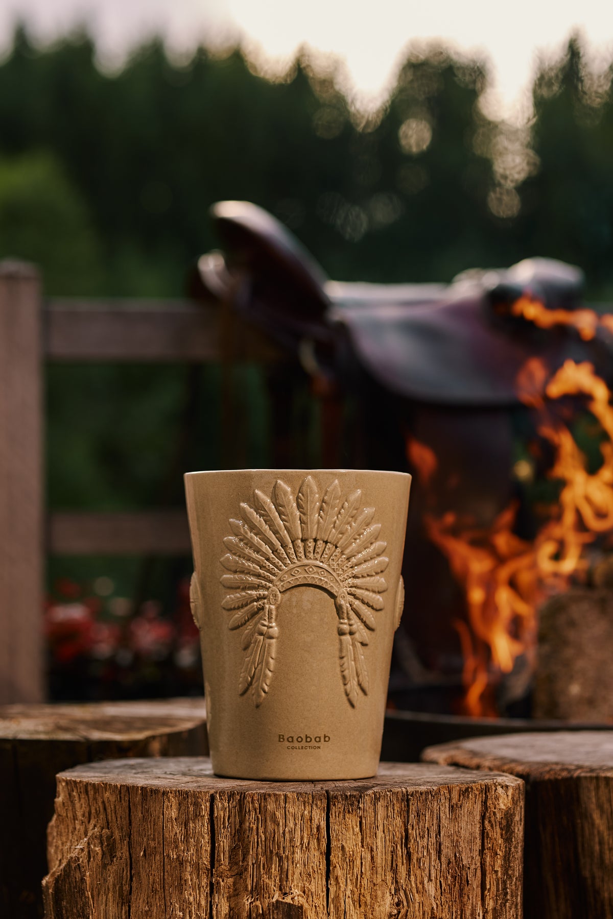 Bougie Baobab Crazy Horse sur une souche, devant un feu de bois en plein air
