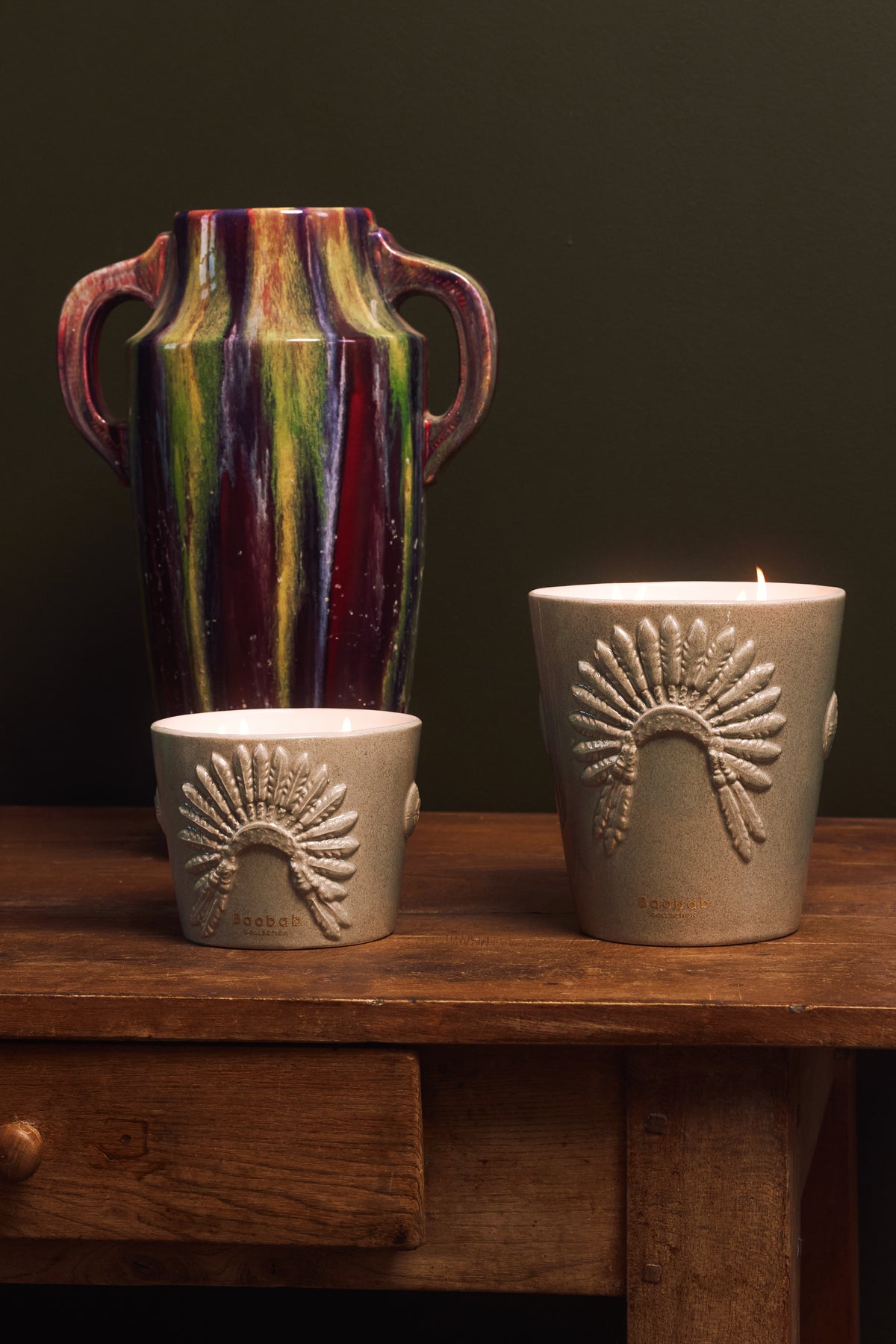 Deux bougies Baobab Crazy Horse allumées sur une console en bois ancienne, près d'un vase en céramique