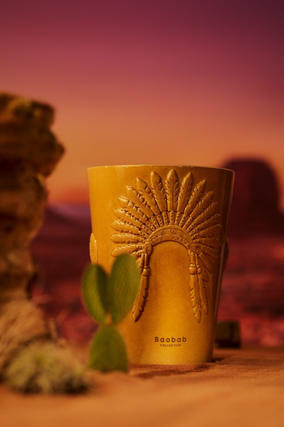 Bougie Baobab Geronimo dans un décor de désert au coucher du soleil, entre rochers et cactus